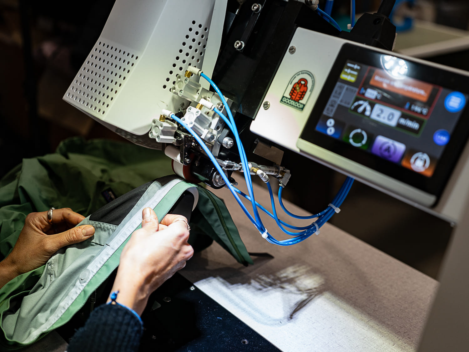 Collage de bandes étanches sur une veste imperméable à l’aide d’une presse thermocolleuse dans l’atelier Goodloop.